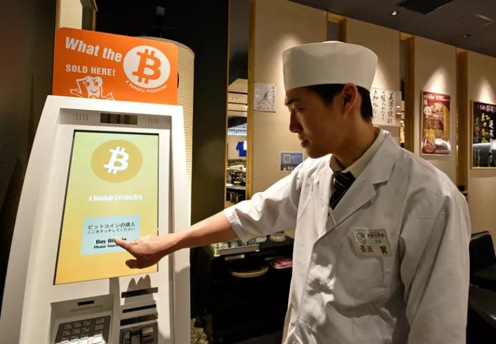 Ciudadanos pasan frente a un poster de Bitcoin en la entrada de un almacén de Bic Camera electronics en Tokio, Japón, hoy, jueves 01 de junio de 2017. EFE