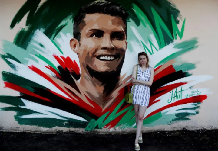 La artista rusa Julia Antipova posa frente al mural que creó de Cristiano. Foto: EFE