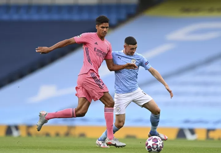 Raphael Varane intenta frenar a Phil Foden. /Foto: EFE